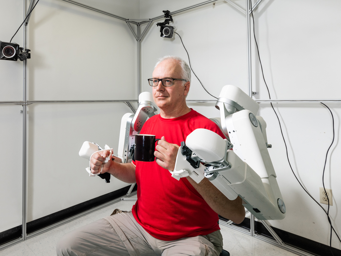 two students looking at and holding robot arm