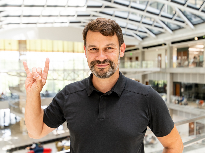 Donald Siegel making hook em horns sign with hand and smiling