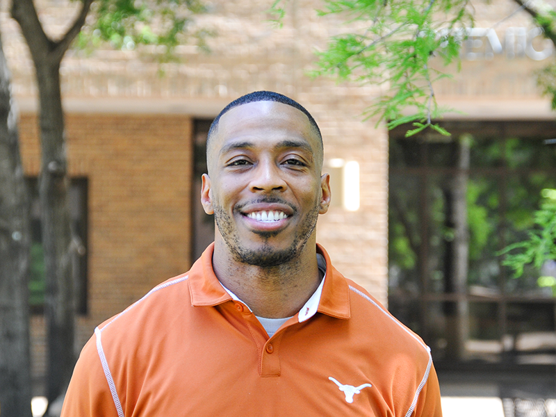 Sam Kirkland smiling in front of Mechanical Engineering building on UT Austin campus.