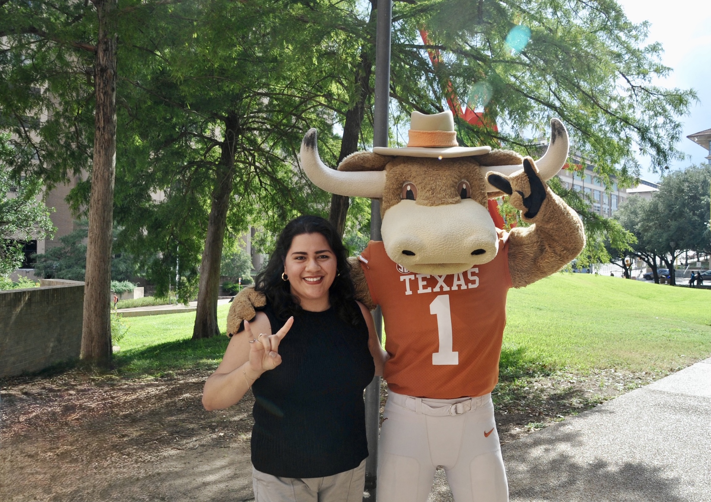 Mechanical engineering student stands outside with Hook Em mascot