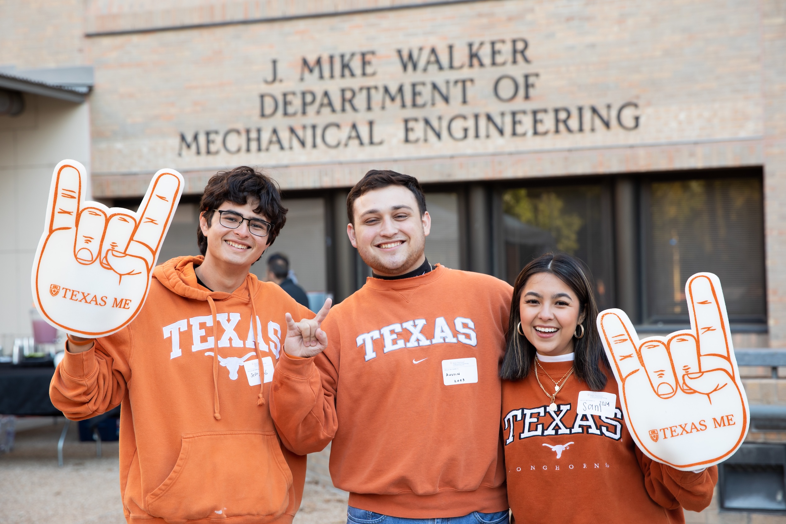 three mechanical engineering UT Austin students with foam fingers at a taligate