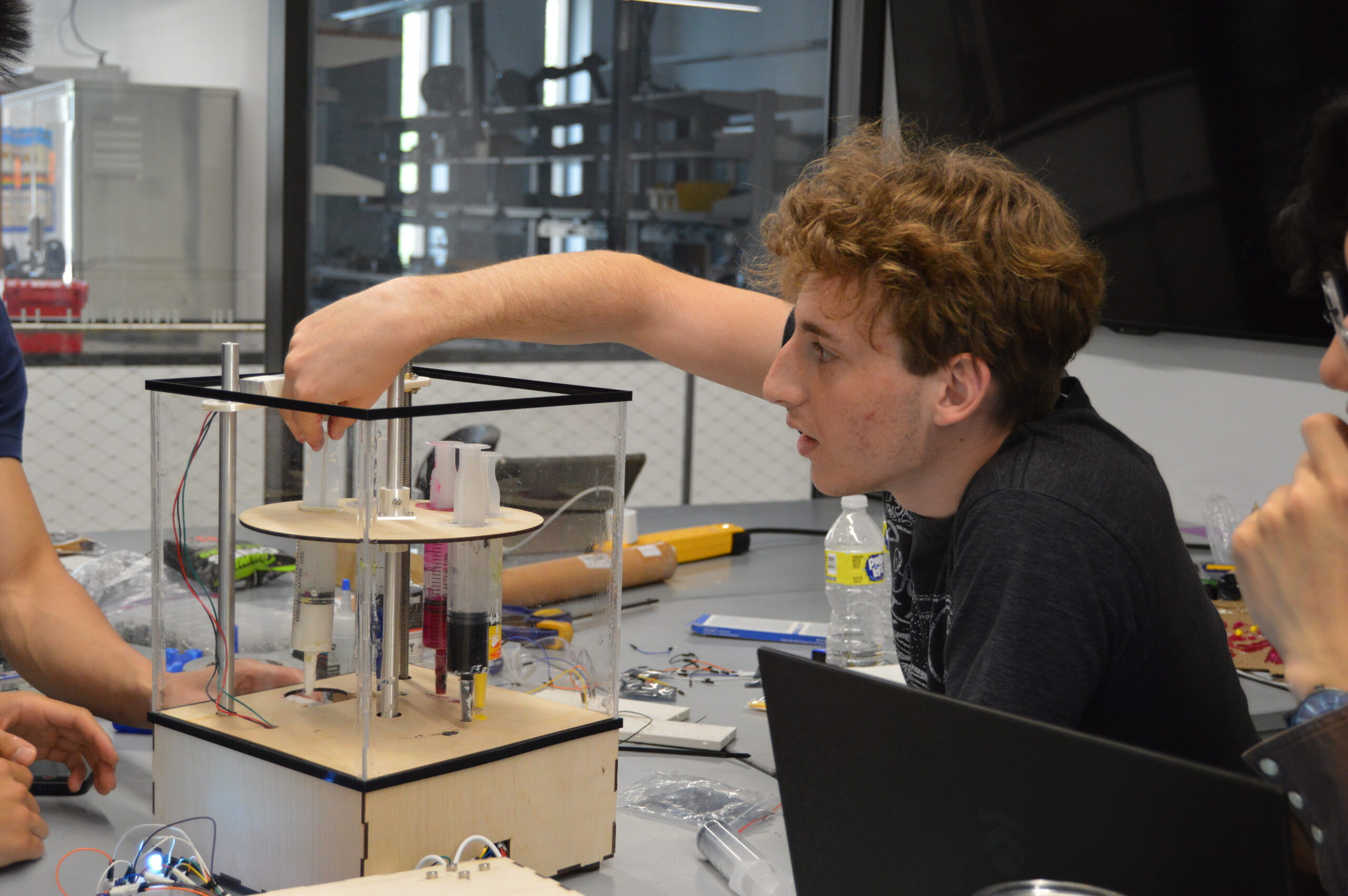 mechanical engineering student with his hand inside a glass box 