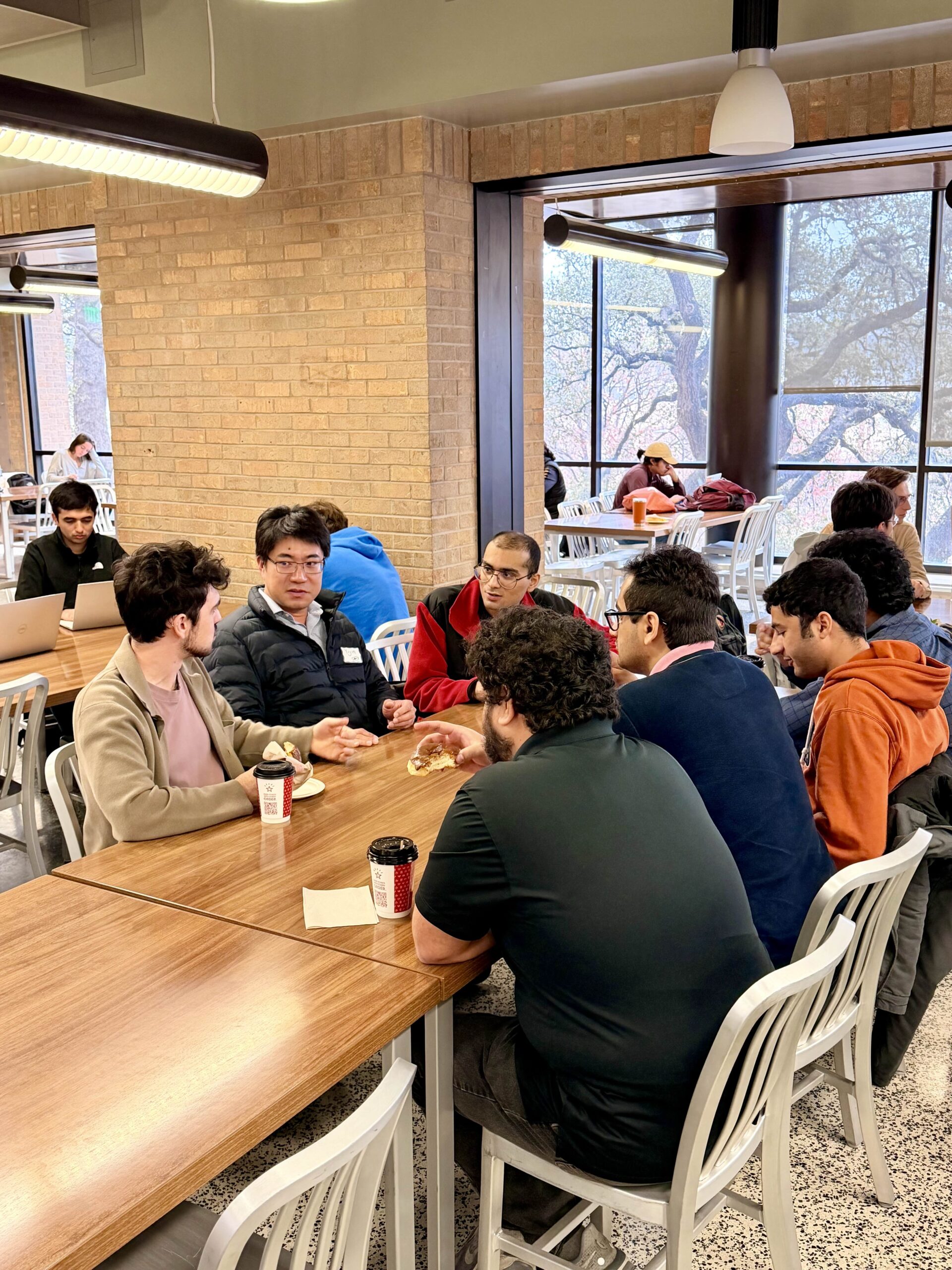 Group of students and faculty chatting a table